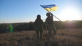 Dolly shot of young woman and man in military uniform waving flag of Ukraine against sunset. Female and male soldier of Royalty Free Stock Photo