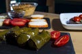 Dolma, delicious Casucasian and Turkish cuisine, vine leaves stuffed with minced meat and rice. traditional hummus cream and Royalty Free Stock Photo