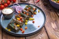 Dolma in grape leaves on a platter on a brown wooden background, decorated with spices, chili peppers, cherry tomatoes Royalty Free Stock Photo