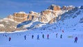 Skiers on the slopes, early morning, with Sella group in the background, lit at sunrise, in Dolomiti Superski domain, Italy Royalty Free Stock Photo
