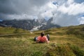 Dolomites. Man laying on the grass enjoying Baita Segantini mountain with Cimon della Pala peak, refuge and lake in