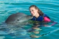 Dolphin kiss young woman in blue water. Smiling woman swimming with dolphin. Blue ocean water background Royalty Free Stock Photo