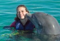 Dolphin kiss young woman in blue water. Smiling woman swimming with dolphin. Blue ocean water background Royalty Free Stock Photo