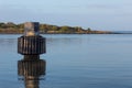 Dolphin pier piling, tube and padded ring mooring in still water, blue sky