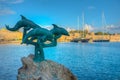 Dolphin statue in front of an ancient fortification at Rhodes in Royalty Free Stock Photo