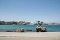 A dolphin statue on the rock in the water by the roadside, opposite of the Rhodes castle