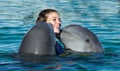 Dolphins kiss young woman in blue water. Smiling woman swimming with dolphin. Blue ocean water background