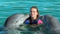 Dolphins kiss young woman in blue water. Smiling woman swimming with dolphin. Blue ocean water background