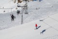 Double-chair ski lift with people over the ski slopes on a sunny winter day