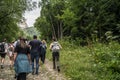 Dombay, Russia 26 July 2020: Group of people go hiking in wooded and hilly area. Rear view of tourists walking on rocky