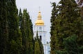 The dome with the cross and the clock of the Christian Church surrounded by a corridor of trees - green coniferous arborvitaes Royalty Free Stock Photo