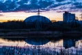 The dome of an inflatable sports complex and the support of a power line against the sunset sky