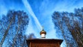 The dome of the Orthodox church with a cross, bare tree branches and blue sky with white clouds on a background in a Royalty Free Stock Photo