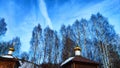 The dome of the Orthodox church with a cross, bare tree branches and blue sky with white clouds on a background in a Royalty Free Stock Photo