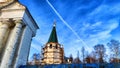 The dome of the Orthodox church with a cross, big colums and blue sky with white clouds on a background in a spring day