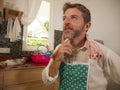 Domestic chores lifestyle portrait of 30s to 40s happy and attractive man wearing kitchen apron thinking what to cook doing