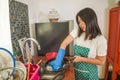 Domestic chores lifestyle portrait of young tired and stressed Asian Chinese woman in cook apron washing dishes at kitchen sink Royalty Free Stock Photo