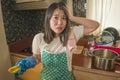 Domestic chores lifestyle portrait of young tired and stressed Asian Chinese woman in cook apron washing dishes at kitchen sink Royalty Free Stock Photo