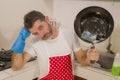 Domestic chores stress - young attractive overworked and stressed home cook man in red apron hating dishwashing feeling upset and Royalty Free Stock Photo