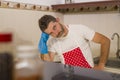 Domestic chores stress - young attractive overworked and stressed home cook man in red apron hating dishwashing feeling upset and Royalty Free Stock Photo