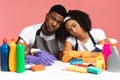Domestic Chores Stress. Tired black couple sitting at table among cleaning supplies
