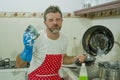 Domestic chores stress - young attractive overworked and stressed home cook man in red apron hating dishwashing feeling upset and Royalty Free Stock Photo