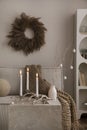 Domestic and cozy christmas living room interior with corduroy sofa, white shelf, candlestick with candle, christmas wearth,