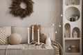 Domestic and cozy christmas living room interior with corduroy sofa, white shelf, christmas wearth, decoration, gifts and