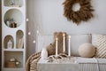 Domestic and cozy christmas living room interior with corduroy sofa, white shelf, christmas wearth, decoration, gifts and