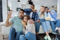 Frightened millennial friends watching scary movie or thriller, holding popcorn, covering their faces in horror at home Royalty Free Stock Photo