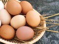 Domestic hens eggs in basket on old wooden texture background. Natural white and red brown eggs. Closeup, top view Royalty Free Stock Photo