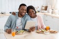 Domestic Leisure. African Couple Eating Breakfast And Using Digital Tablet In Kitchen Royalty Free Stock Photo