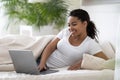 Domestic Leisure. Beautiful Young Black Woman Using Laptop While Lying In Bed