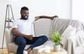 Positive relaxed african guy sitting on couch at home