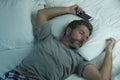 Domestic lifestyle high angle portrait of young attractive and tired man sleeping on bed holding mobile phone in internet and Royalty Free Stock Photo