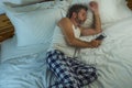 Domestic lifestyle high angle portrait of young attractive and tired man sleeping on bed holding mobile phone in internet and Royalty Free Stock Photo