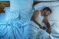 Domestic lifestyle high angle portrait of young attractive and tired man sleeping on bed holding mobile phone in internet and Royalty Free Stock Photo