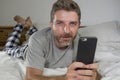 Domestic lifestyle portrait of young happy and attractive man lying on bed at home smiling cheerful and relaxed using mobile phone