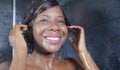 Domestic lifestyle portrait of young happy and beautiful black African American woman smiling happy taking a shower at home Royalty Free Stock Photo