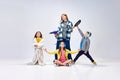 Domestic lifestyle. Portrait of young woman, other and little kids, children posing in home wear against grey studio