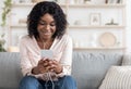 Domestic Pastime. Relaxed African American Girl Listening Music With Smartphone And Earphones