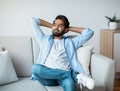 Domestic Rest. Arab Man Leaning Back On Sofa With Hands Behind Head