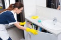 Domestic worker opening sink cabinet Royalty Free Stock Photo