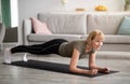 Domestic workout concept. Athletic senior woman standing in elbow plank on yoga mat at home Royalty Free Stock Photo