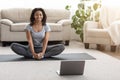 Domestic Yoga. Smiling African Woman Meditating At Home In Front Of Laptop