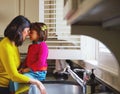 Domestically blissfull. a young mother and her daughter bonding by the kitchen sink. Royalty Free Stock Photo