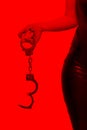 Dominatrix holding handcuffs in red light BDSM