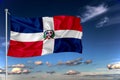 Dominicana national flag waving in the wind against deep blue sky. International relations concept