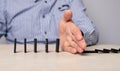 Domino effect stopping. Businessman hand closeup protecting domino pieces from falling. Successful intervention in Royalty Free Stock Photo