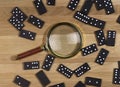 Domino game pieces scattered on wood desk with gold magnifying glass, top view Royalty Free Stock Photo